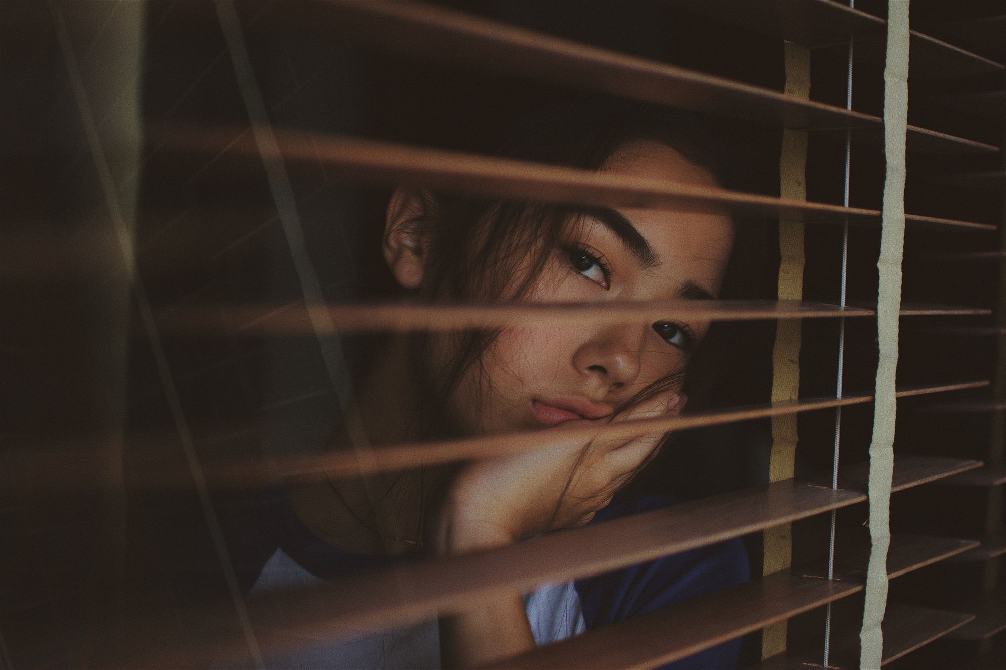 Girl gazing out window with anxiety 