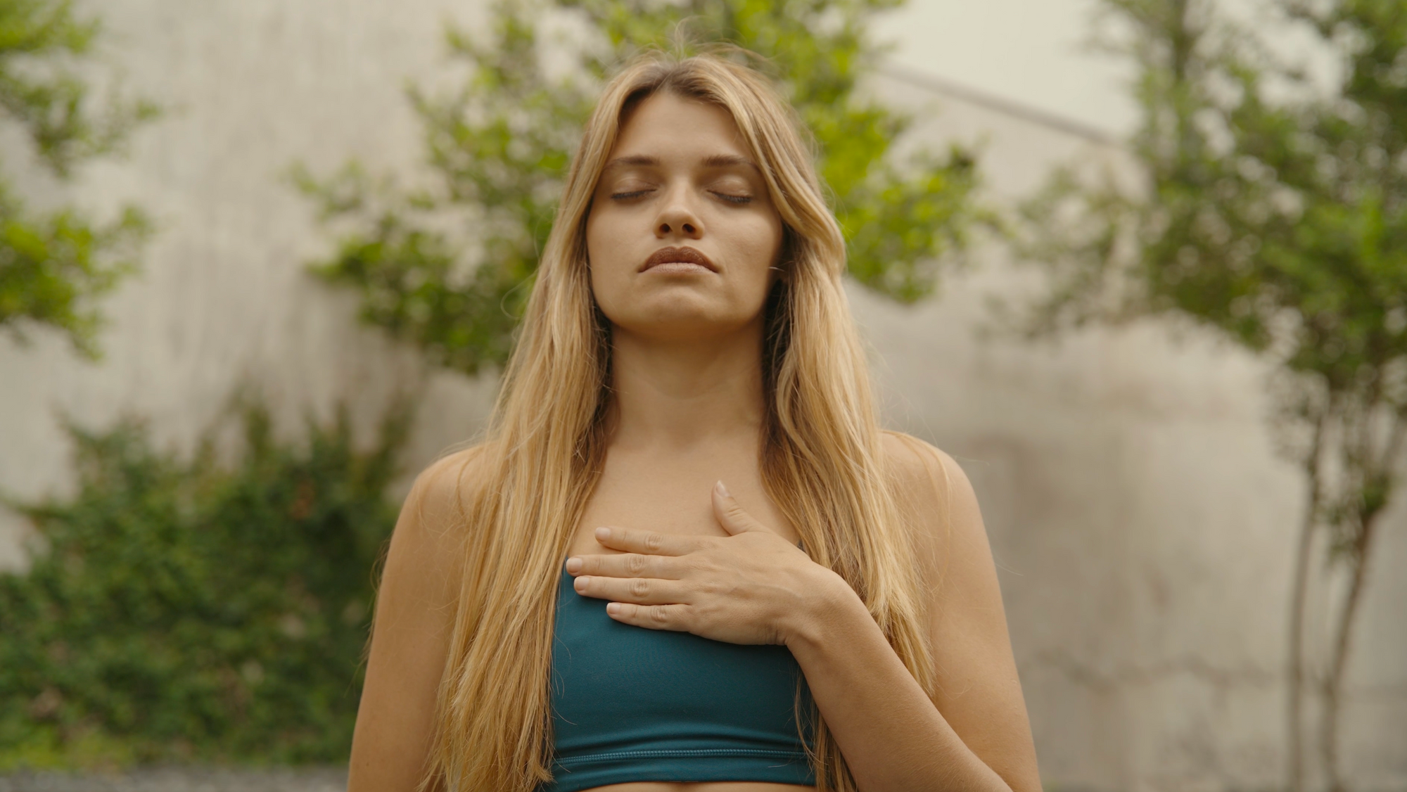 Young woman with hand on her heart meditating, engaging in integration practices for psychedelic therapy