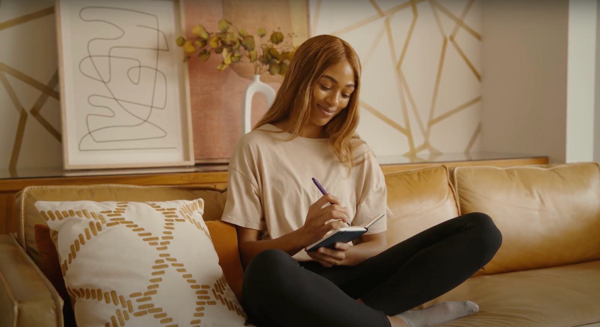 Young woman smiling and writing in journal as part of mindfulness practices for psychedelic therapy integration