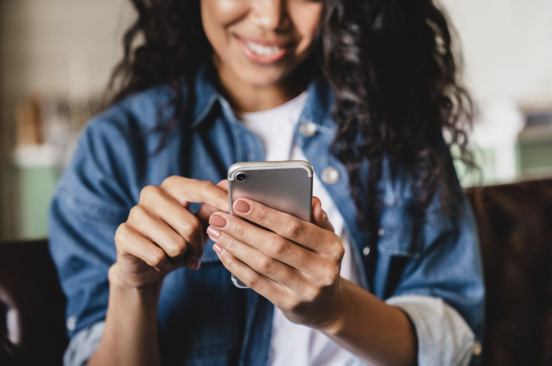 Young woman looking at phone smiling from text message support program for anxiety