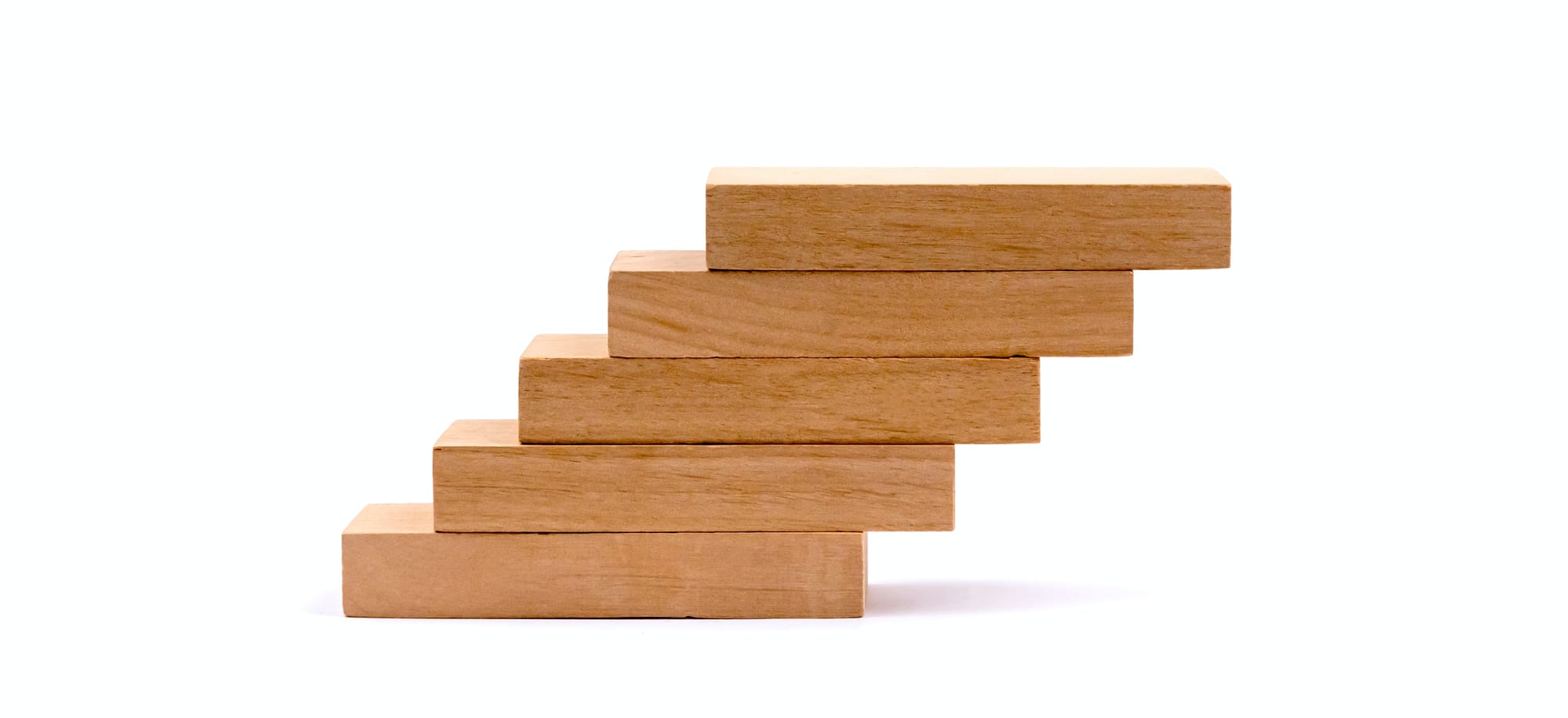 Pile of wooden blocks arranged as steps on minimal white background